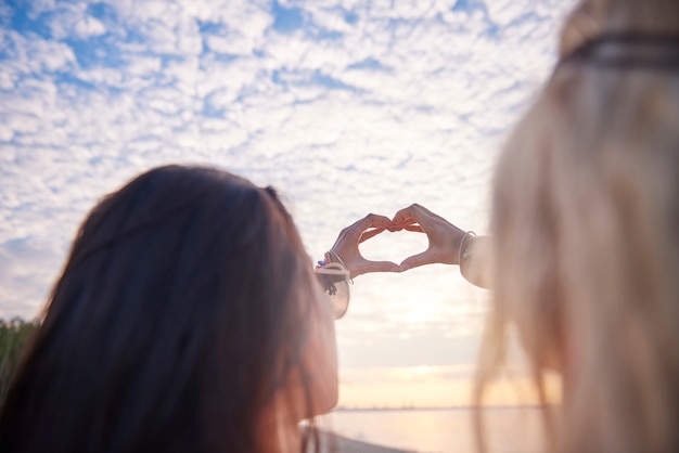 Gratis foto jonge mooie vrouwen die een hart maken sigs met handen