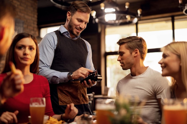 Jonge ober die creditcardbetaling accepteert van zijn gast die de restaurantrekening betaalt