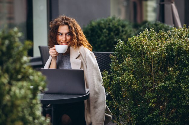 Jonge onderneemster die aan een computer buiten het koffie werkt