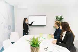 Gratis foto jonge onderneemster die presentatie geeft aan haar collega's in commerciële vergadering