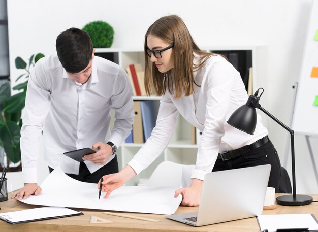 Jonge onderneemster die project bespreken met haar mannelijke collega op Witboek over het bureau