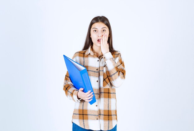 Jonge onderneemster met blauwe houder die zich met verraste uitdrukking bevindt.