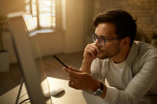 Jonge ondernemer die gegevens op een desktop-pc analyseert terwijl hij op kantoor werkt