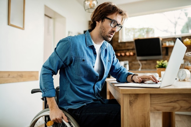 Jonge ondernemer in rolstoel die thuis aan een computer werkt.