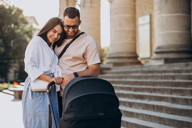 Jonge ouders die met hun baby in een wandelwagen lopen