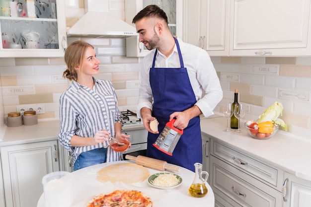 Gratis foto jonge paar kokende pizza in keuken