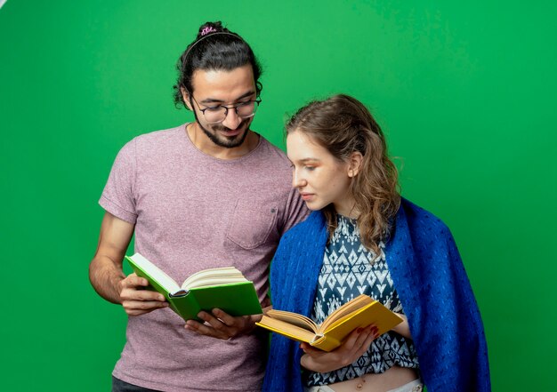 Jonge paarman en vrouw die met deken open boeken houden gelukkige en positieve status over groene achtergrond