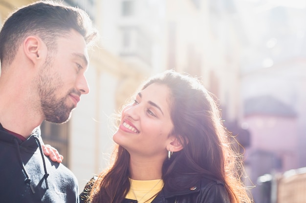 Gratis foto jonge positieve kerel dichtbij gelukkige dame op straat