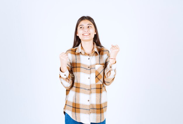 jonge positieve vrouw die zich op witte muur bevindt.