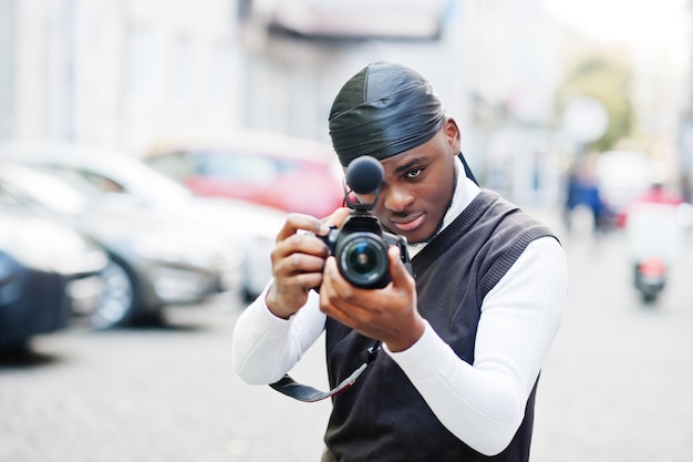 Jonge professionele afro-amerikaanse videograaf met professionele camera met pro-apparatuur Afro-cameraman met zwarte duraq die video's maakt