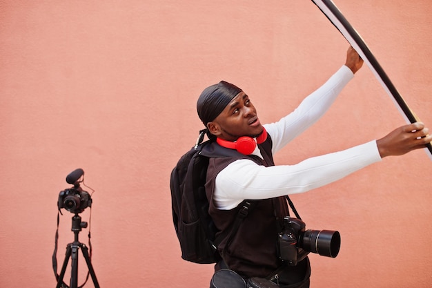 Jonge professionele afro-amerikaanse videograaf met professionele camera met pro-apparatuur Afro-cameraman met zwarte duraq die video's maakt