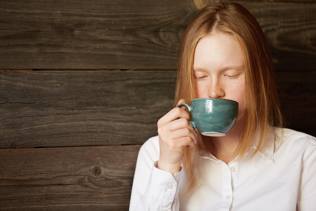 Jonge roodharige vrouw in café