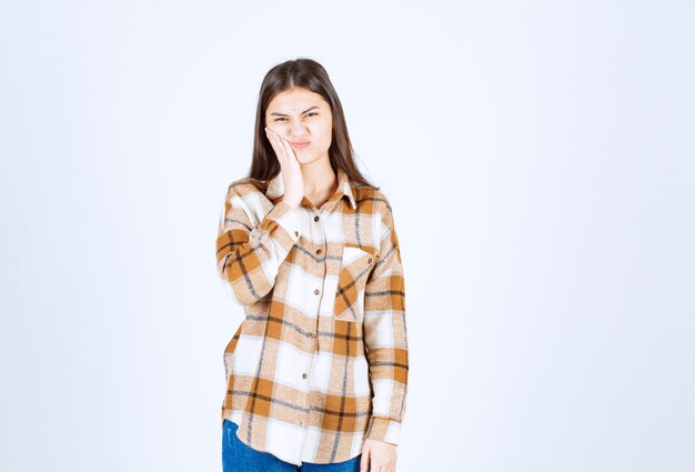 Jonge schattige vrouw in casual kleding met kiespijn op witte muur.