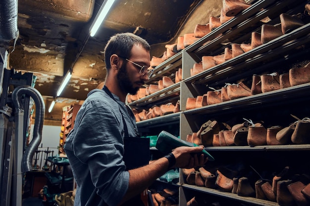 Jonge schoenmaker zoekt speciale schoenvorm voor zijn nieuwe project.