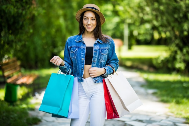 Jonge schoonheid vrouw met boodschappentassen wandelen in het stadspark na bezoek winkel