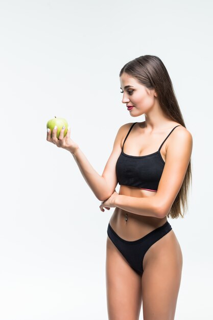 Jonge slanke vrouw die groene appel houdt. Geïsoleerd op een witte muur. Concept van gezonde voeding en de controle van overgewicht.