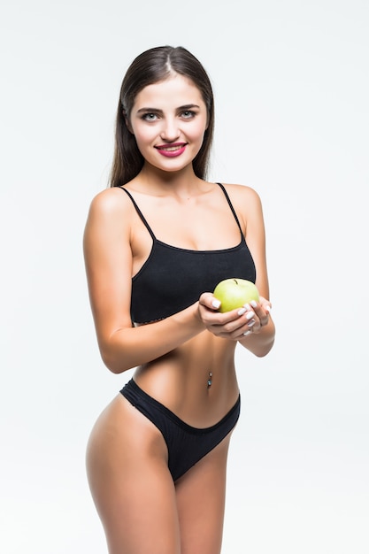 Jonge slanke vrouw die rode appel houdt. Geïsoleerd op een witte muur. Concept van gezonde voeding en de controle van overgewicht.