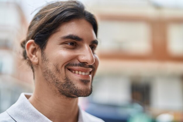 Jonge spaanse man glimlachend zelfverzekerd kijkend naar de zijkant op straat