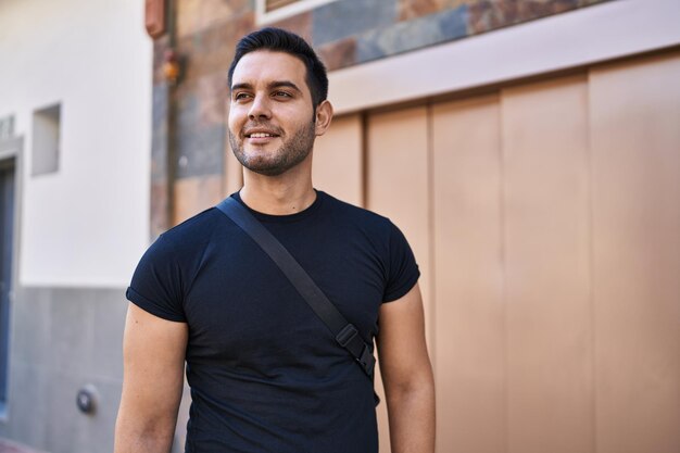 Jonge Spaanse man glimlachend zelfverzekerd staande op straat