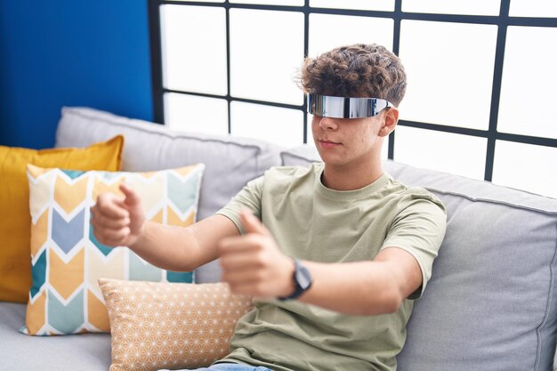 Jonge spaanse tiener die videogame speelt met een virtual reality-bril thuis