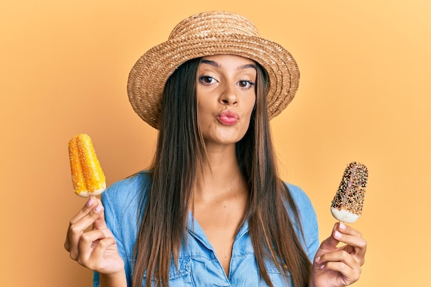 Jonge spaanse vrouw die het roomijs van de de zomerstijl draagt die de camera bekijkt die een kus blaast die mooie en sexy liefdesuiting is