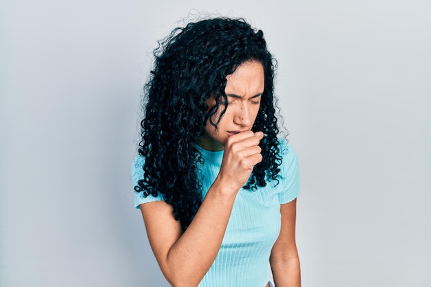 Gratis foto jonge spaanse vrouw met krullend haar, gekleed in een casual blauw t-shirt, zich onwel voelen en hoesten als symptoom voor verkoudheid of bronchitis gezondheidszorgconcept