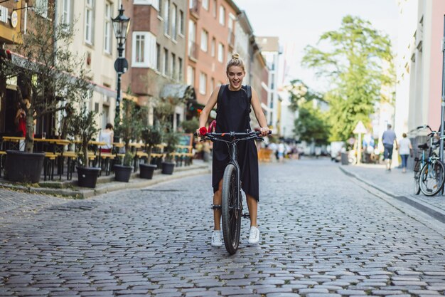 Jonge sportenvrouw op een fiets in een Europese stad. Sporten in stedelijke omgevingen.