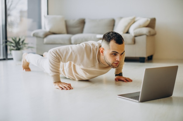 Jonge sportieve man die thuis yoga beoefent