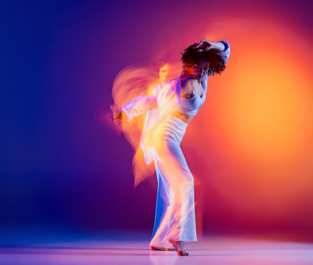 Jonge sportieve mooi meisje hiphop danser dansen geïsoleerd op paarse achtergrond in neonlicht