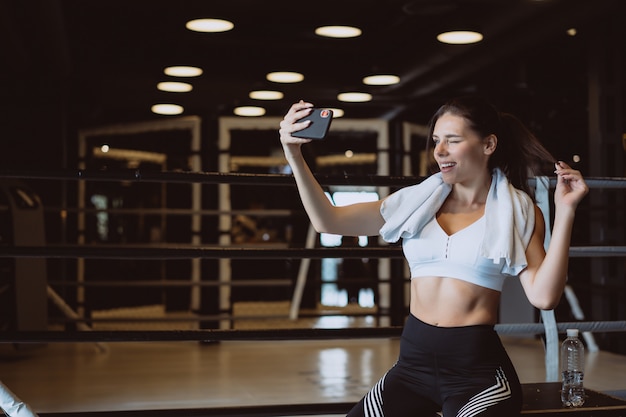 Jonge sportieve vrouw die een selfie met mobiele telefoon nemen bij gymnastiek.