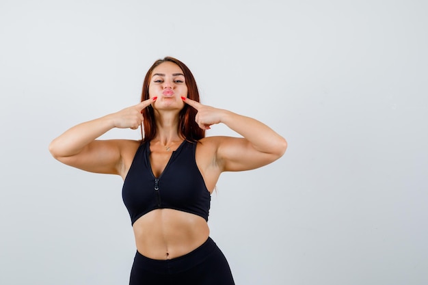 Jonge sportieve vrouw die op haar wangen drukt