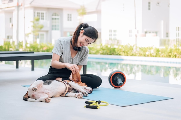 Jonge sportieve vrouw speelt met haar beagle hond na training thuis Premium Foto