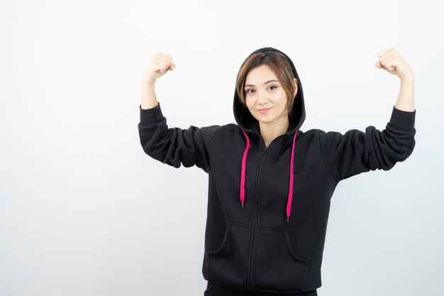 Jonge sportieve vrouw staat en toont haar biceps. Hoge kwaliteit foto