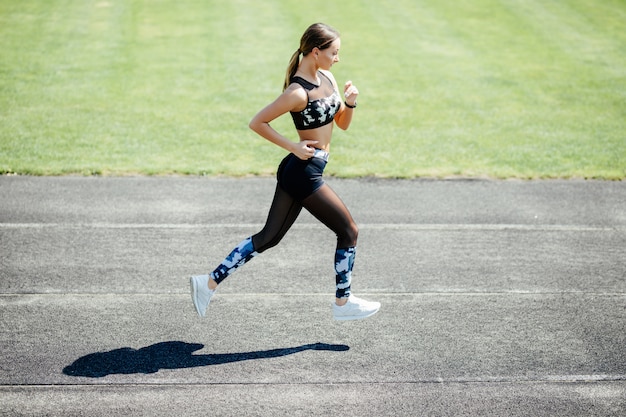 Gratis foto jonge sportvrouw die bij een atletiekstadion lopen