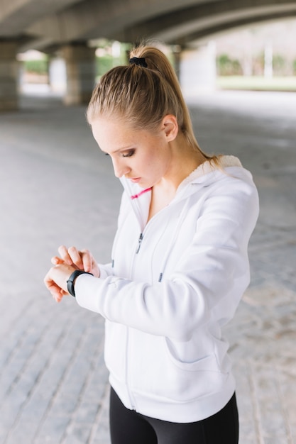 Jonge sportvrouw kijkt naar haar smartwatch.
