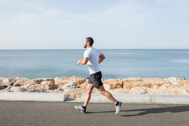 Jonge Sterke Sportieve Man Running On Road Along Sea