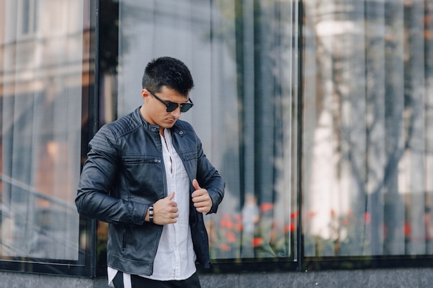 Jonge stijlvolle man in glazen in zwart lederen jas