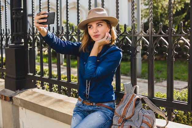 Jonge stijlvolle mooie vrouw die een selfie neemt, gekleed in denimoverhemd en spijkerbroek