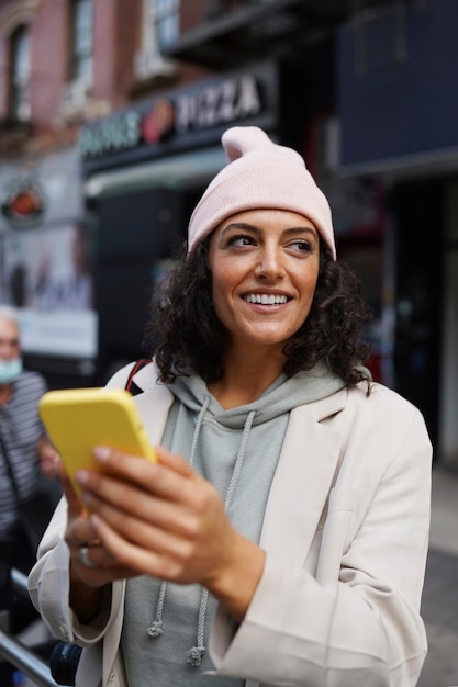 Jonge stijlvolle vrouw in de stad die smartphone gebruikt voor verkenning