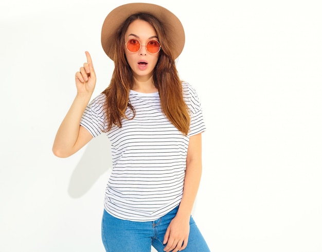 Jonge stijlvolle vrouw model in casual zomer kleding in bruine hoed krijgt goed idee in gedachten