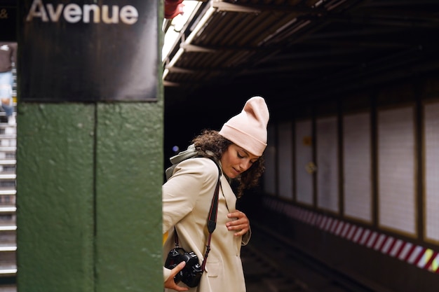 Jonge stijlvolle vrouwelijke fotograaf die de metro in de stad verkent