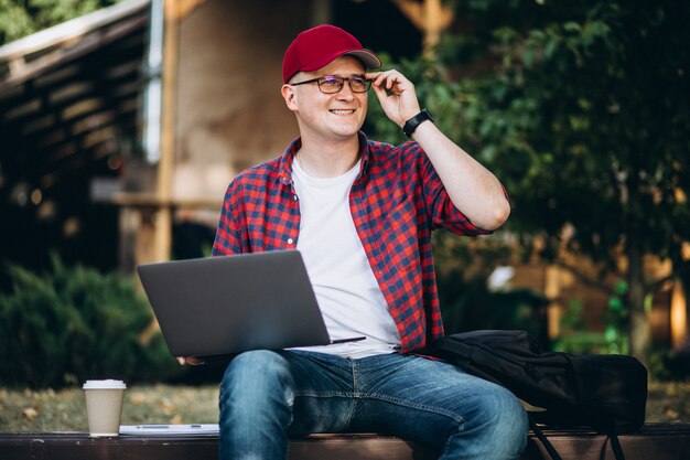 Jonge student die aan een computer buiten het café in park werkt