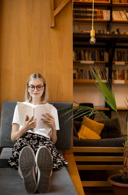 Gratis foto jonge student die een boek leest in de bibliotheek