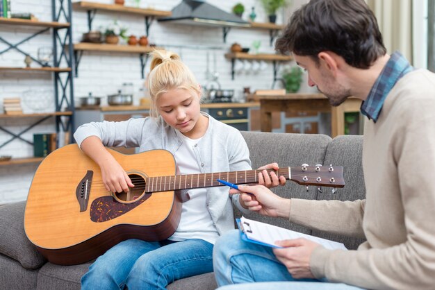 Jonge student die leert hoe de gitaar te houden