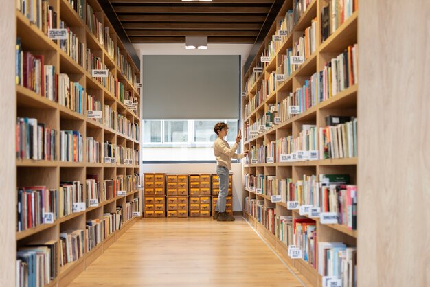 Jonge student op zoek naar een boek in de bibliotheek