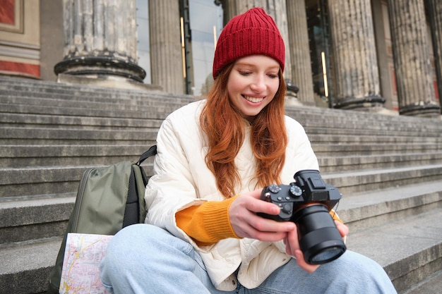 Jonge studentenfotograaf zit op straattrappen en controleert haar foto's op professionele camera's