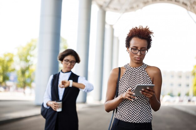 Jonge succesvolle Afrikaanse onderneemster die tablet over commercieel centrum bekijkt.