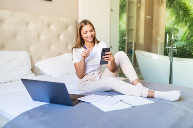 Jonge succesvolle vrouw liggend op een bank met laptop die online rekeningen betaalt, opkijkt en denkt