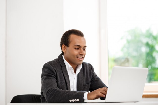 Jonge succesvolle zakenman typen op laptop, zittend op de werkplek