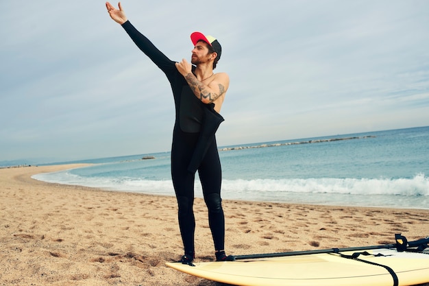 Gratis foto jonge surfer man op strand met surfplank